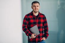 Etudiant en chemise à carreau porte un ordinateur